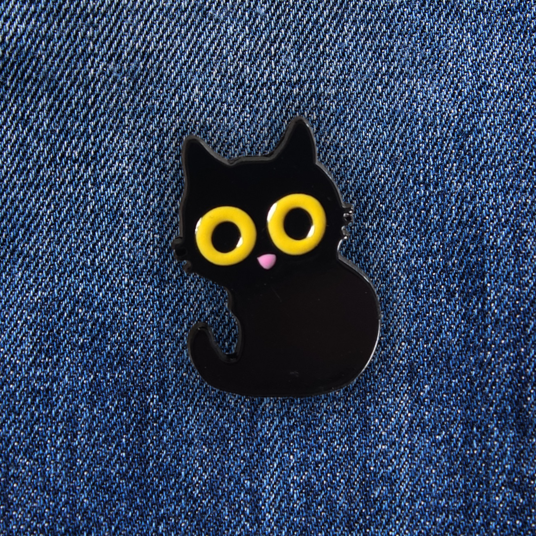 Pins d'un chat noir sur un jean